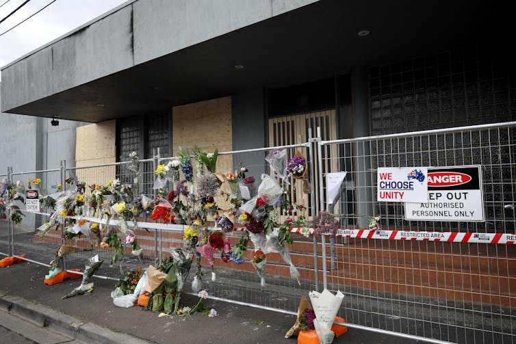 A metal fence with floral tributes attached outside a building