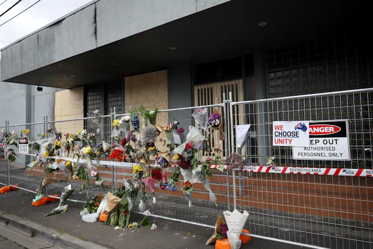 A metal fence with floral tributes attached outside a building