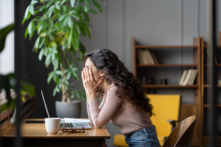 Woman with head in hands in front of laptop