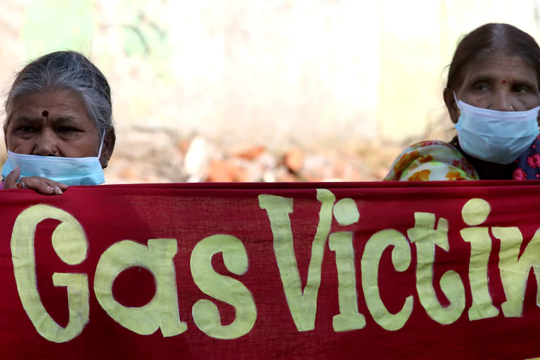 Two women hold a banner reading 'gas victims'.