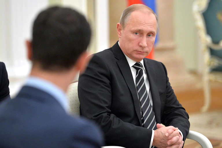 Vladimir Putin looking at Bashar al-Assad.