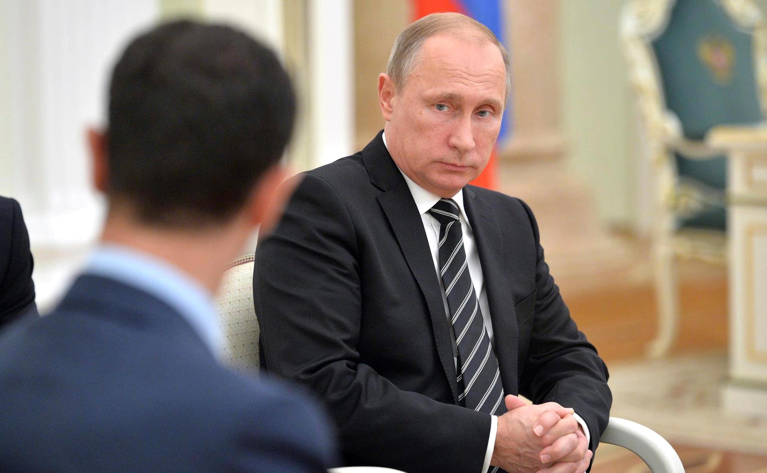 Vladimir Putin looking at Bashar al-Assad.