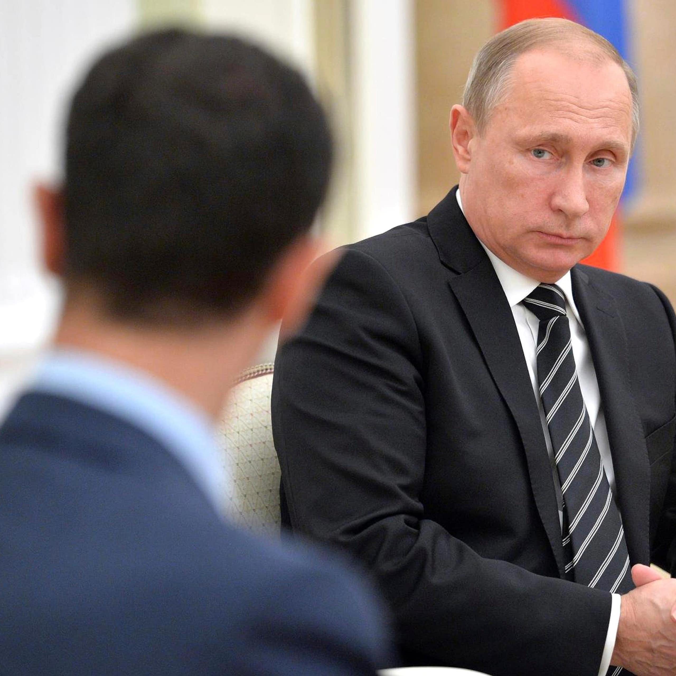 Vladimir Putin looking at Bashar al-Assad.
