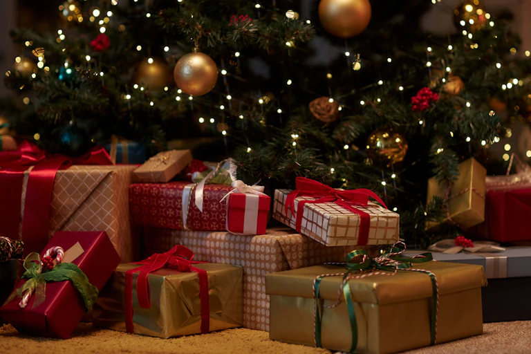 des cadeaux emballés au pied d'un sapin avec des décorations de Noël