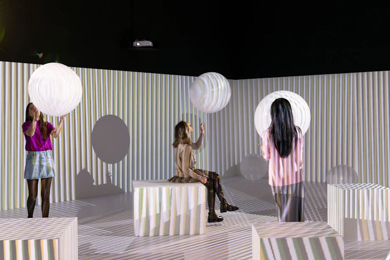 Women looking at large levitating white balls