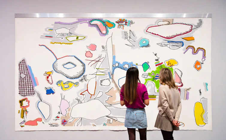 Women looking at a large wall-mounted canvas