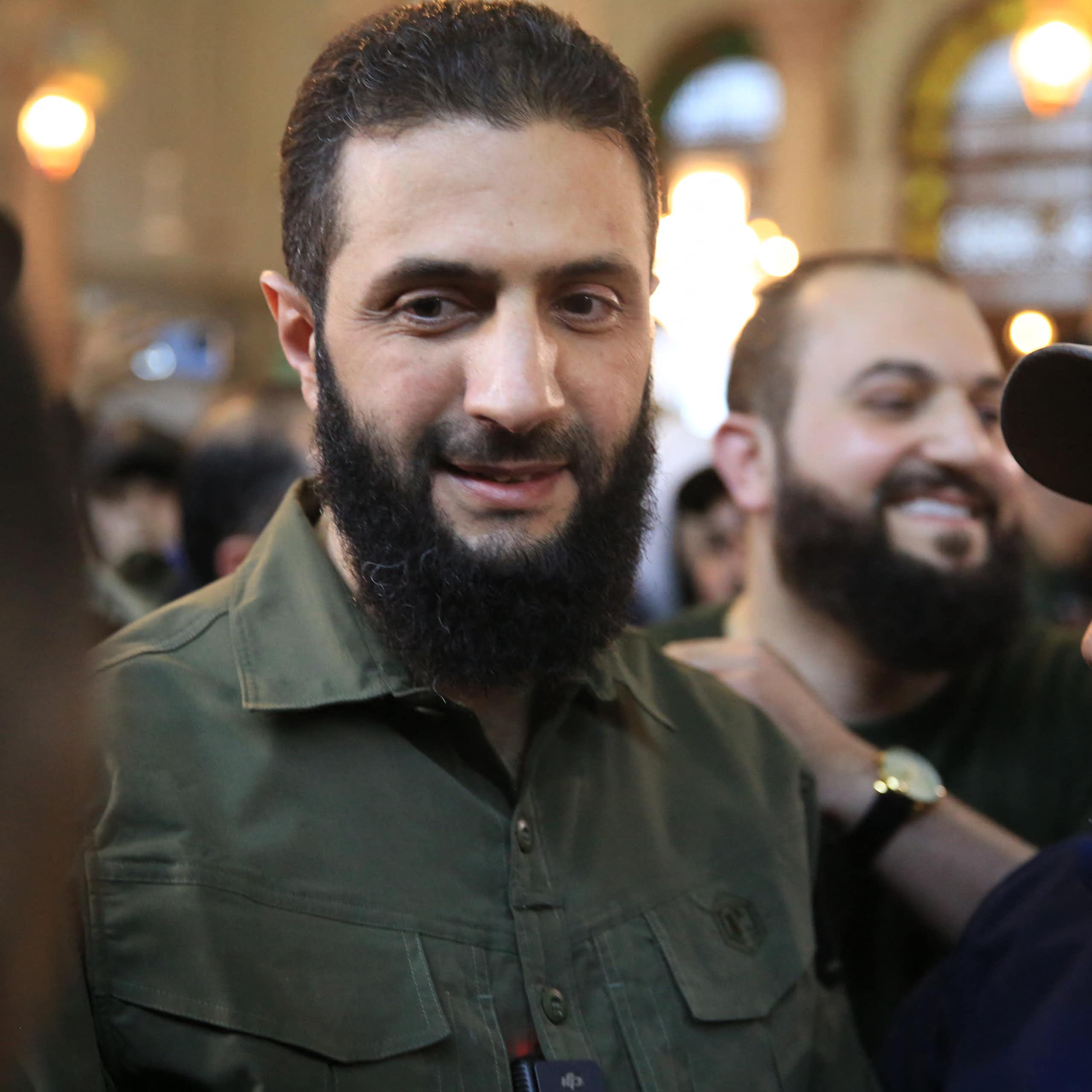 A man with a beard talks to others people.