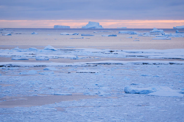 imagem de um oceano gelado com icebergs ao fundo