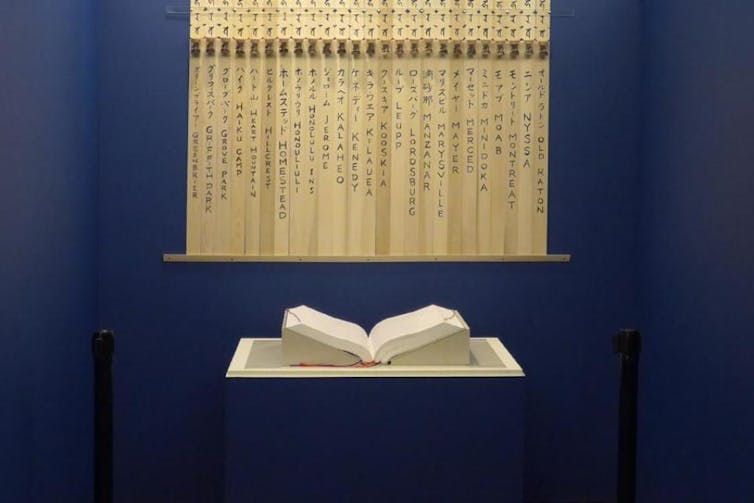 A book sits open on a flat surface, with banners hung behind it.