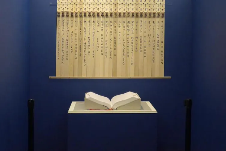 A book sits open on a flat surface, with banners hung behind it.