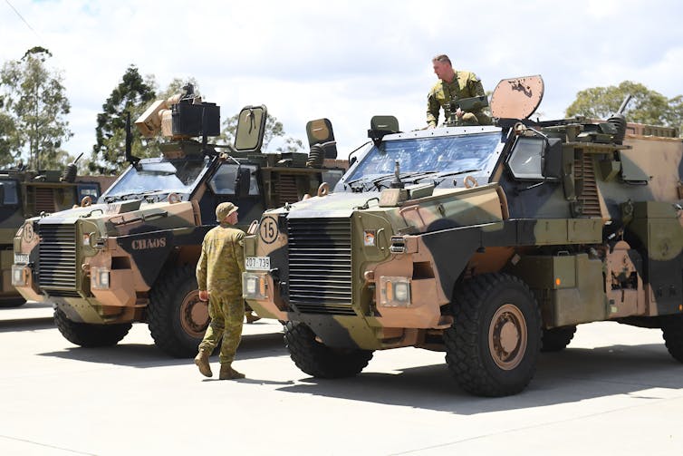 A group of soliders on bushmaster army vehicles.