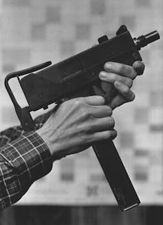 Two hands hold a submachine gun.