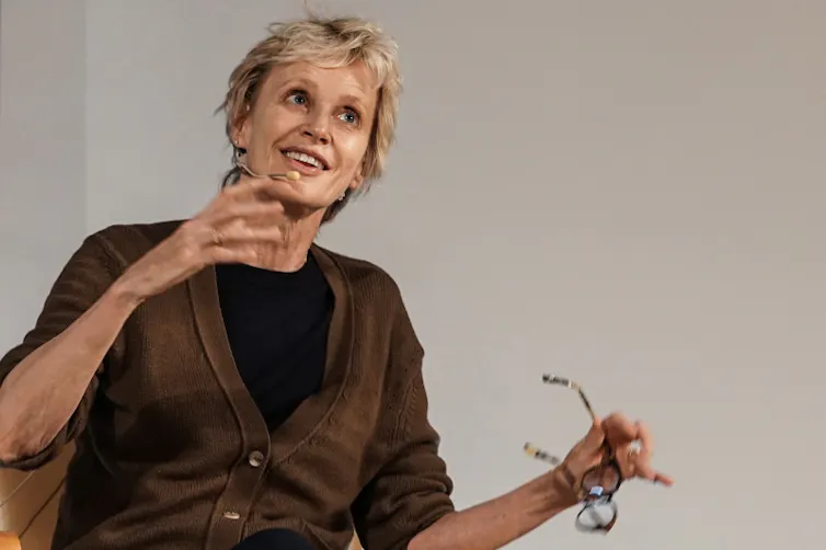 A short-haired, blonde woman, Siri Hustvedt, speaking at a conference.