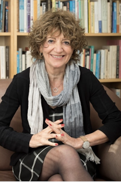 A dark-haired woman sitting with her legs crossed.