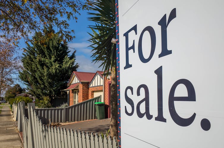 A 'for sale' corflute in front of a brick house in Australia