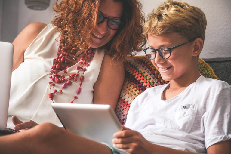Boy and his mother look at a tablet, smiling