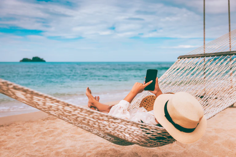 Woman wearing hat lying on a hammock at the beach