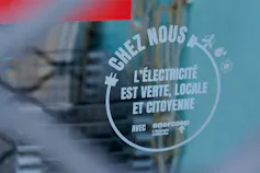 Devanture d’un magasin avec un autocollant où est inscrit « chez nous, l’électricité est verte »