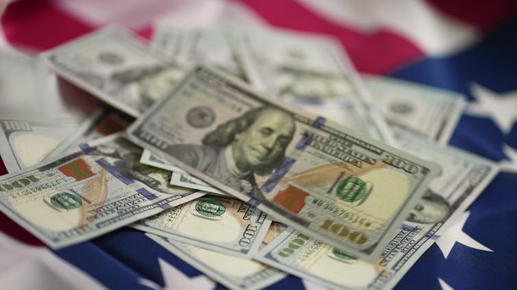 US dollar banknotes on top of a US flag.