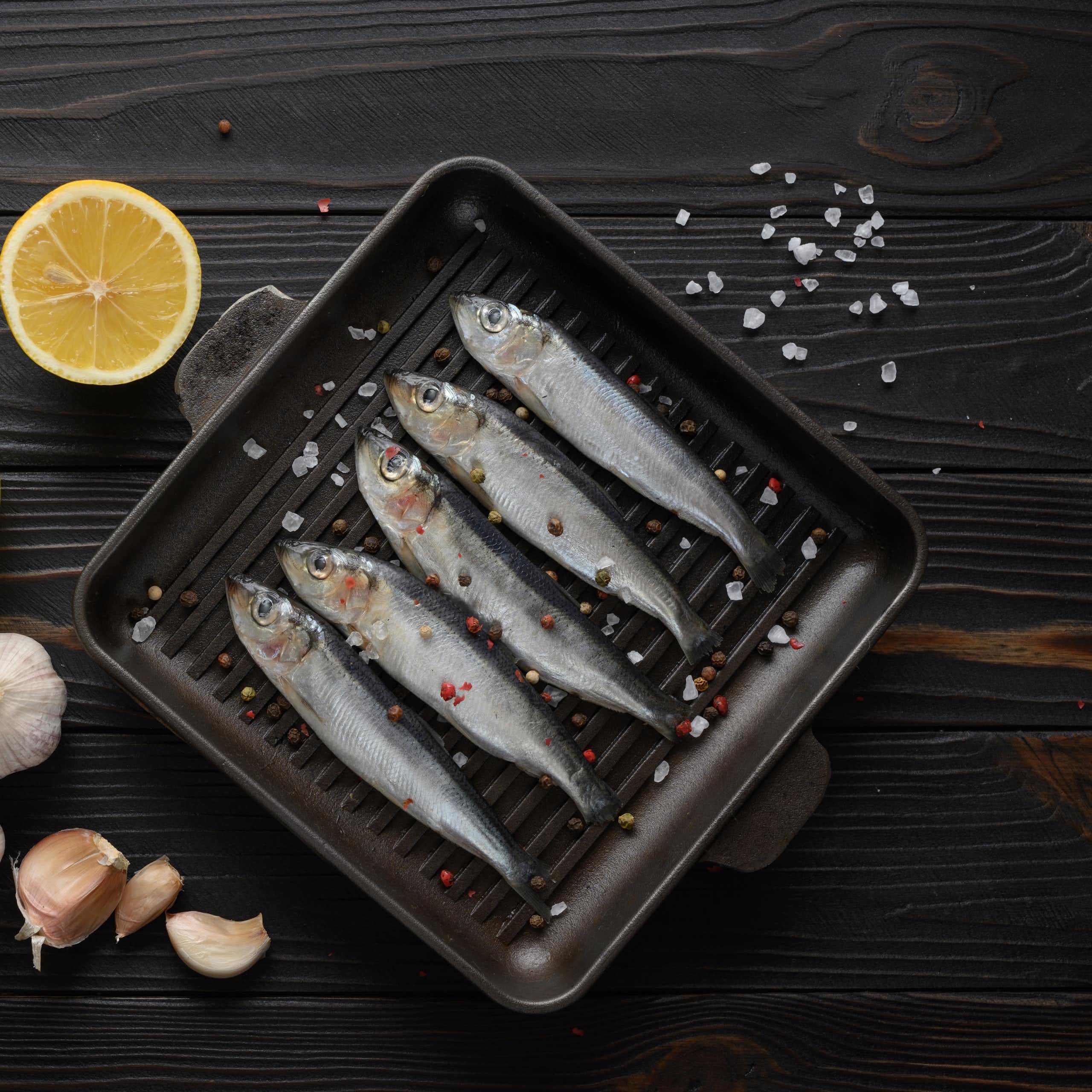 A combination of raw sardines, garlic, lemon and a bottle of oil.