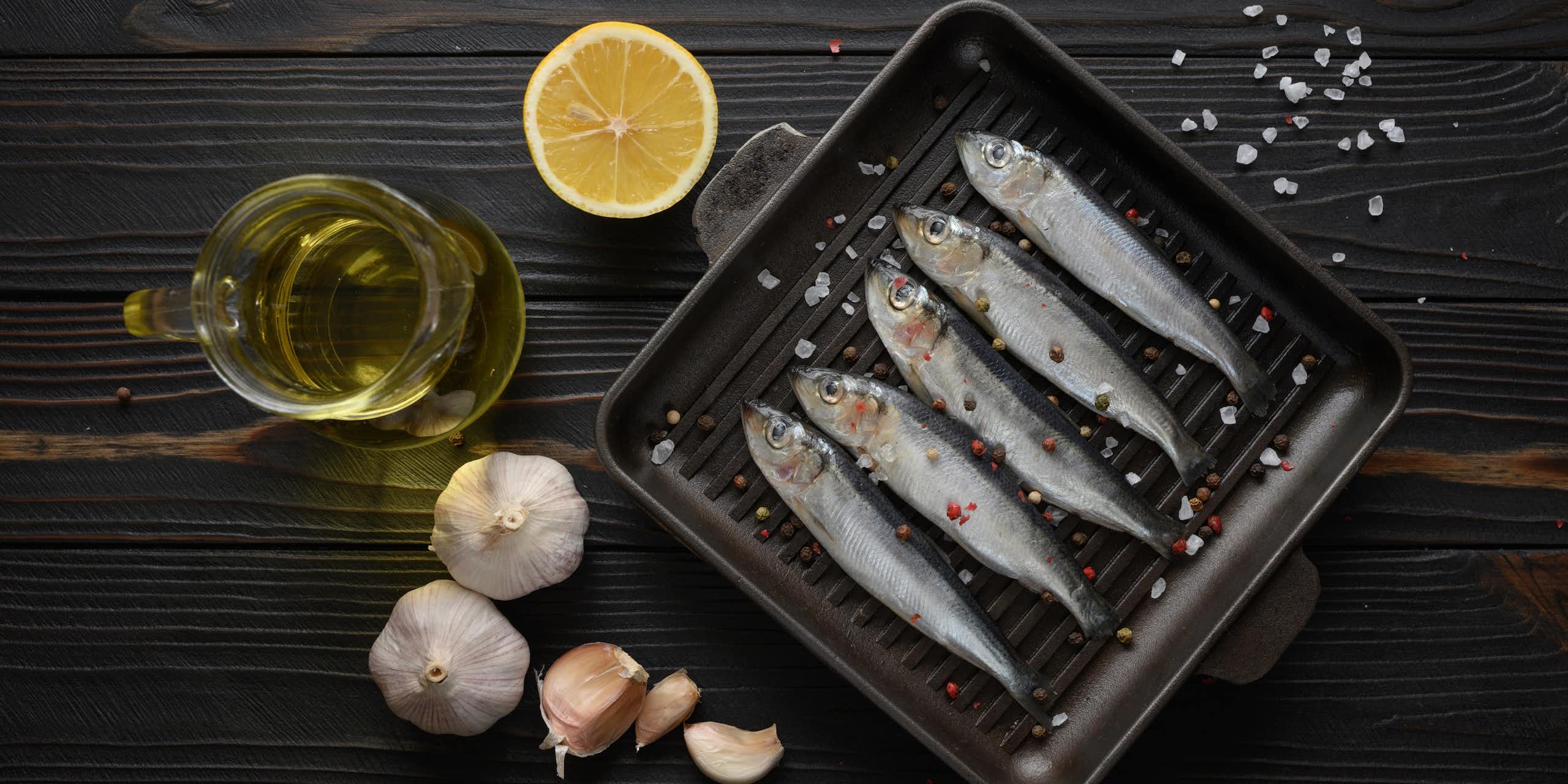 A combination of raw sardines, garlic, lemon and a bottle of oil.