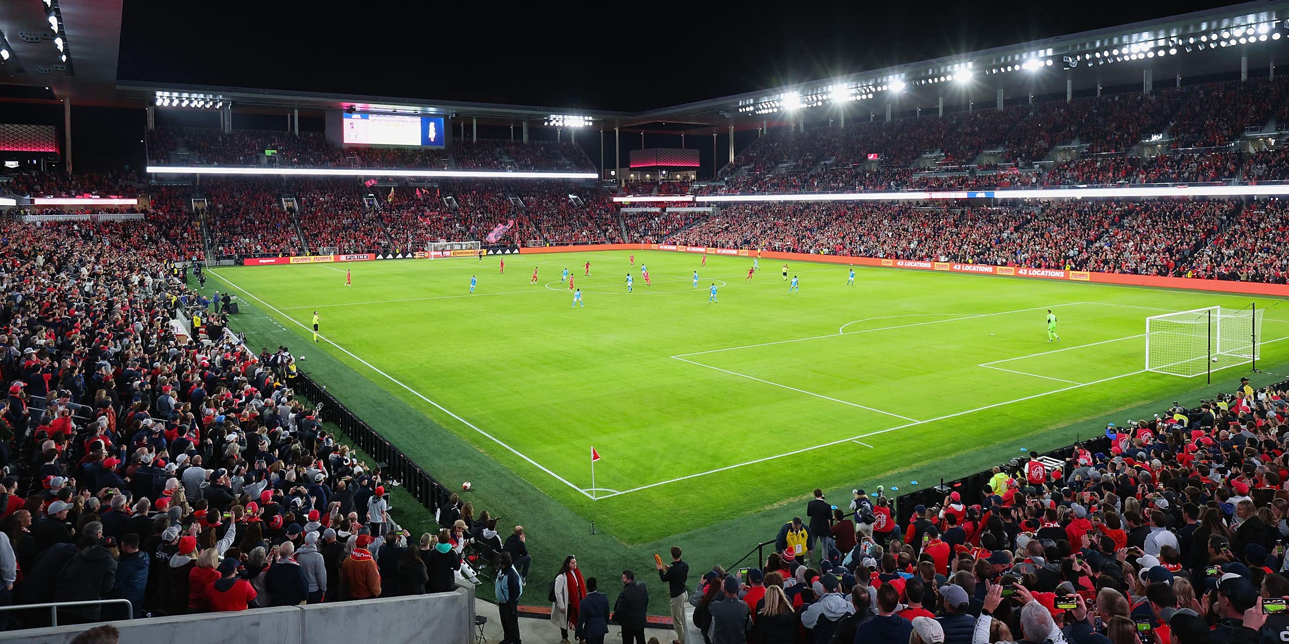 A packed soccer stadium is seen from a high angle at night.