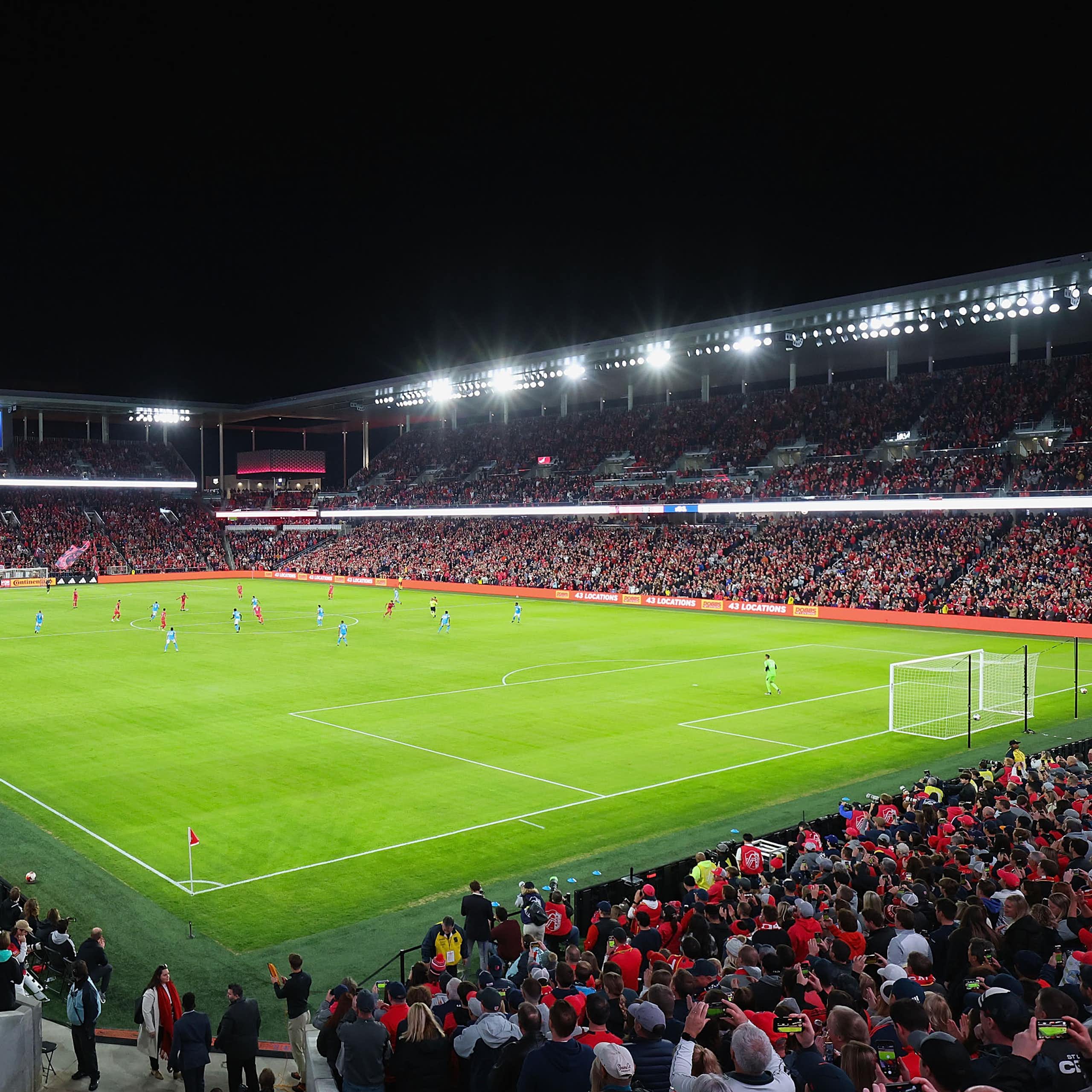A packed soccer stadium is seen from a high angle at night.