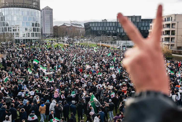 A huge crowd of people in a city plaza, celebrating.