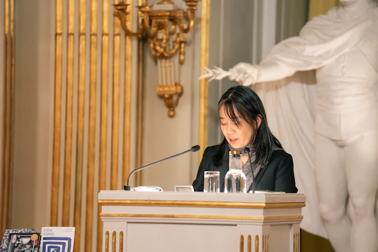 Una mujer ante un atril dando un discurso.