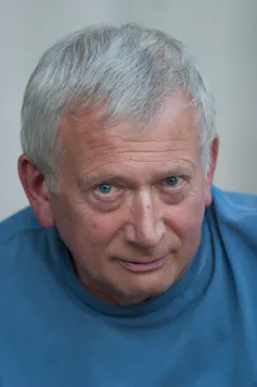 Paul Bailey, an older white man with blue eyes in a blue tshirt looks to camera.