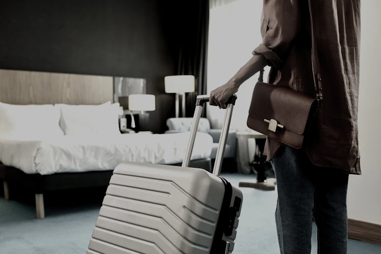 An unidentifable woman with a suitcase in a hotel room