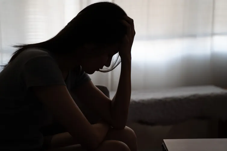 The silhouette of a woman holding her head in her hands