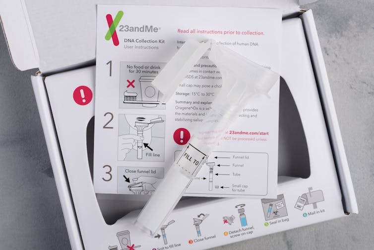 A tube and set of instructions for collection saliva sit on top of an open carboard box