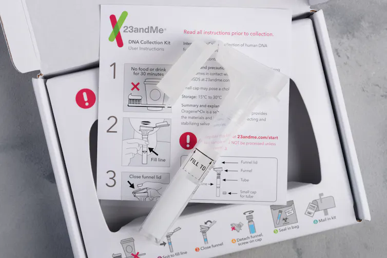 A tube and set of instructions for collection saliva sit on top of an open carboard box