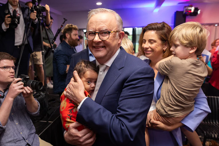 Prime Minister Anthony Albanese holds a tiny baby at a media event.