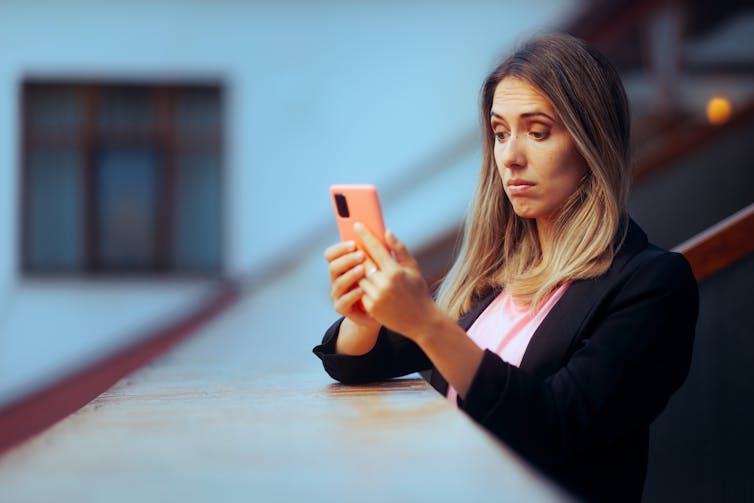 Woman looking at her phone with a sceptical expression.