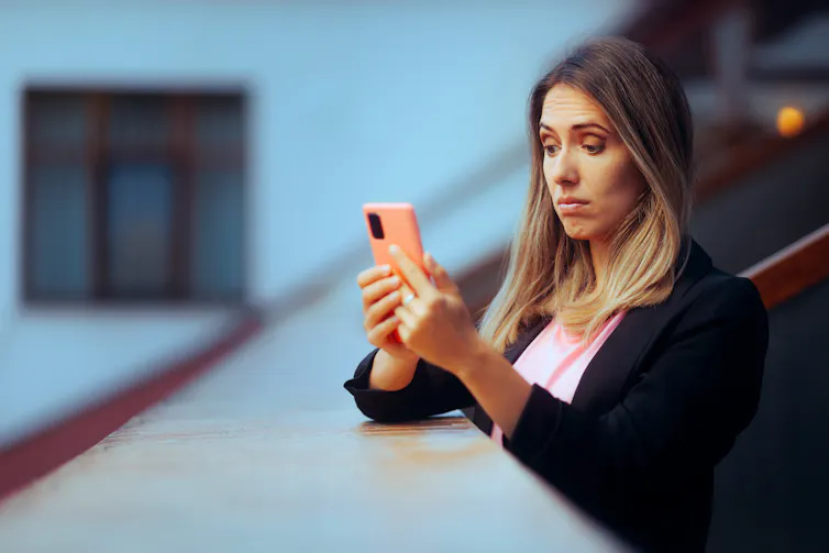 Woman looking at her phone with a sceptical expression.
