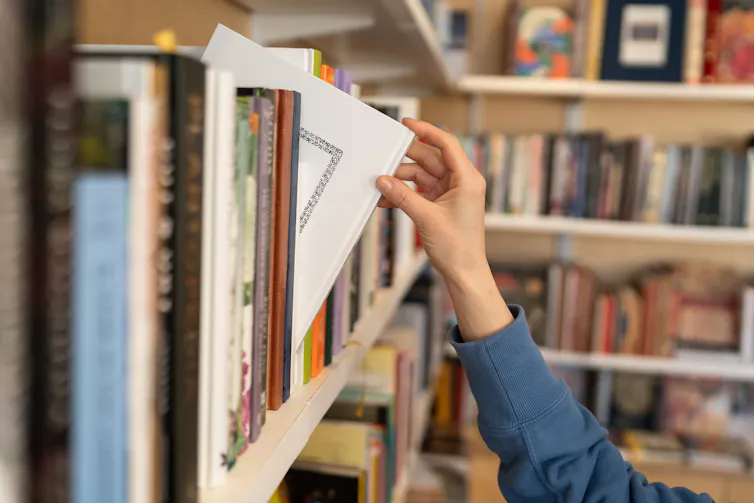 A librarian removing a book from a shelf.