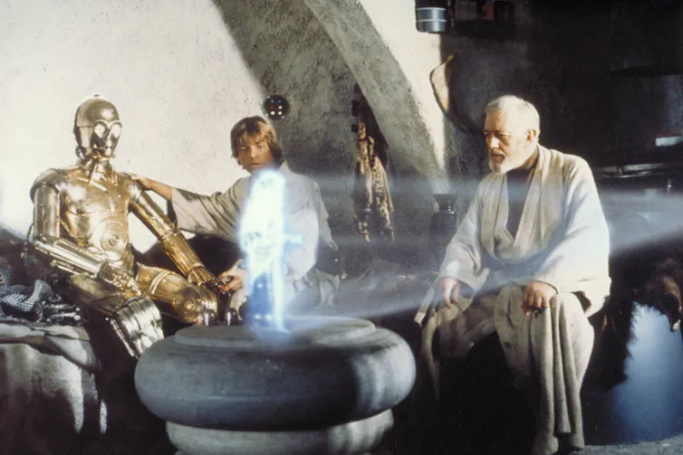 A robot and two men sitting on a couch