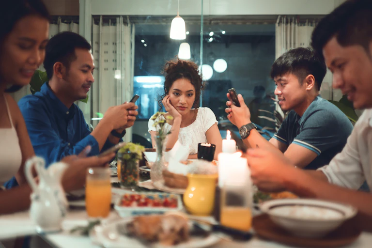 A woman looks bored at the table with her family.