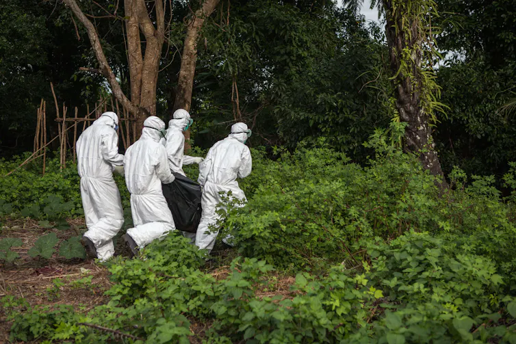 Men in protective suits carrying body