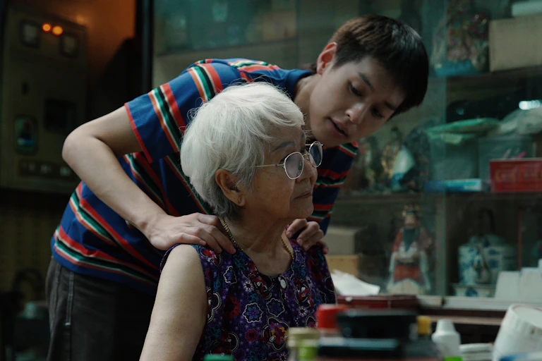 A young man holding his grandmother's shoulders.