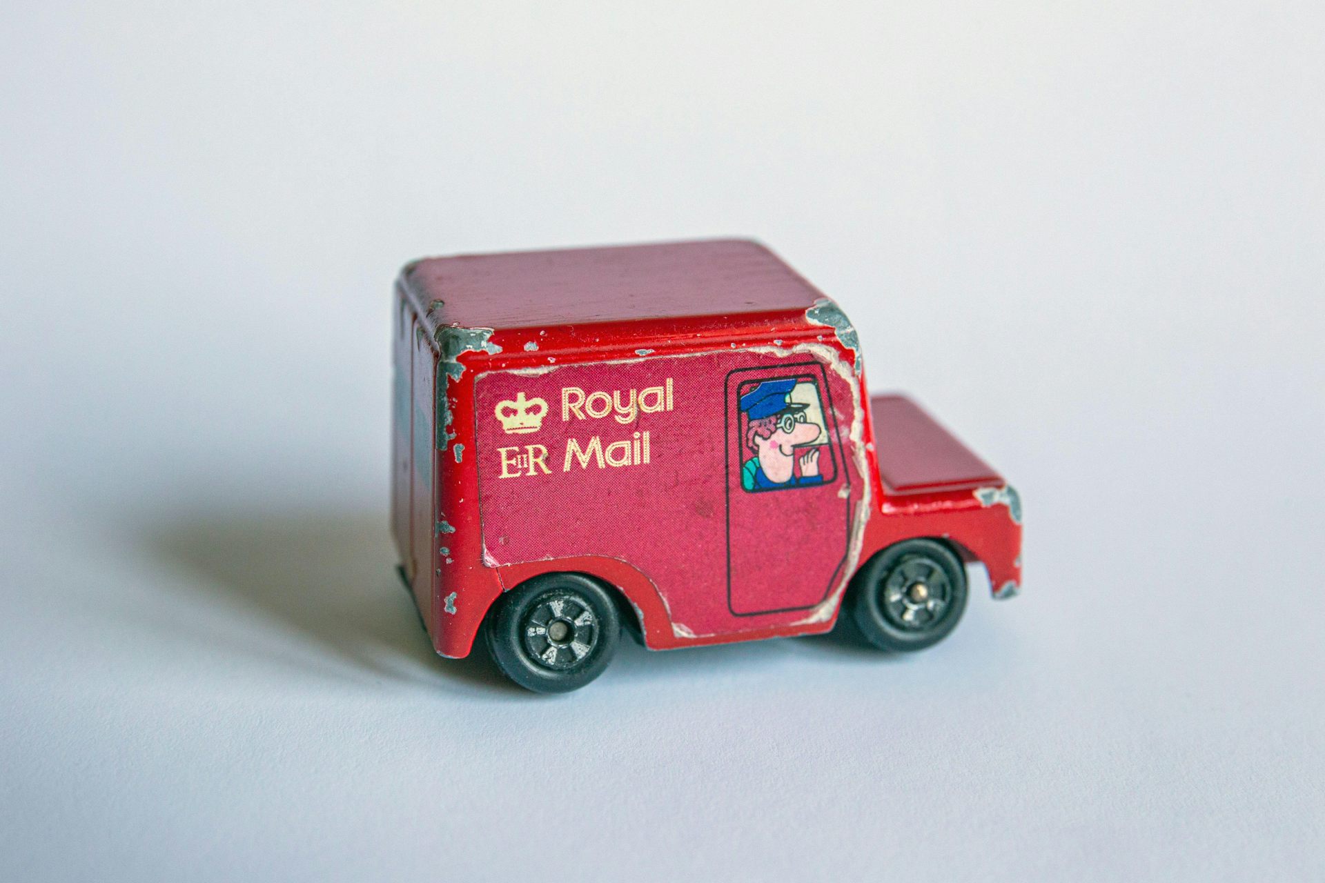 A toy post van with a drawing of Postman Pat in the window. 