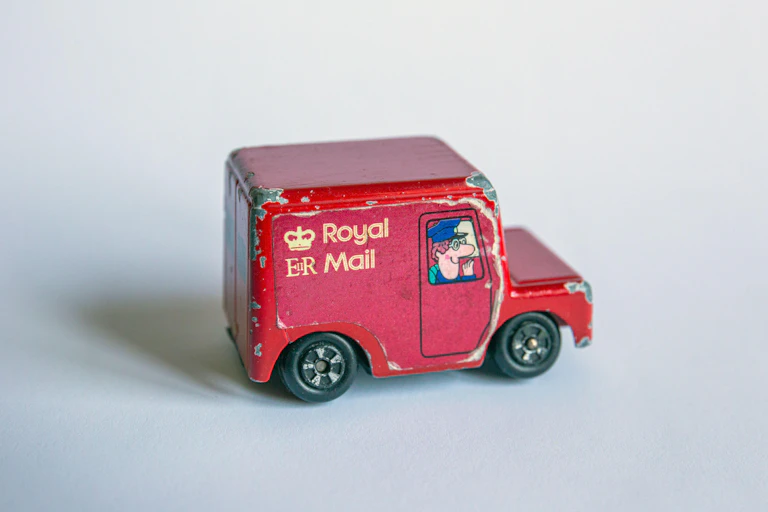 A toy post van with a drawing of Postman Pat in the window.