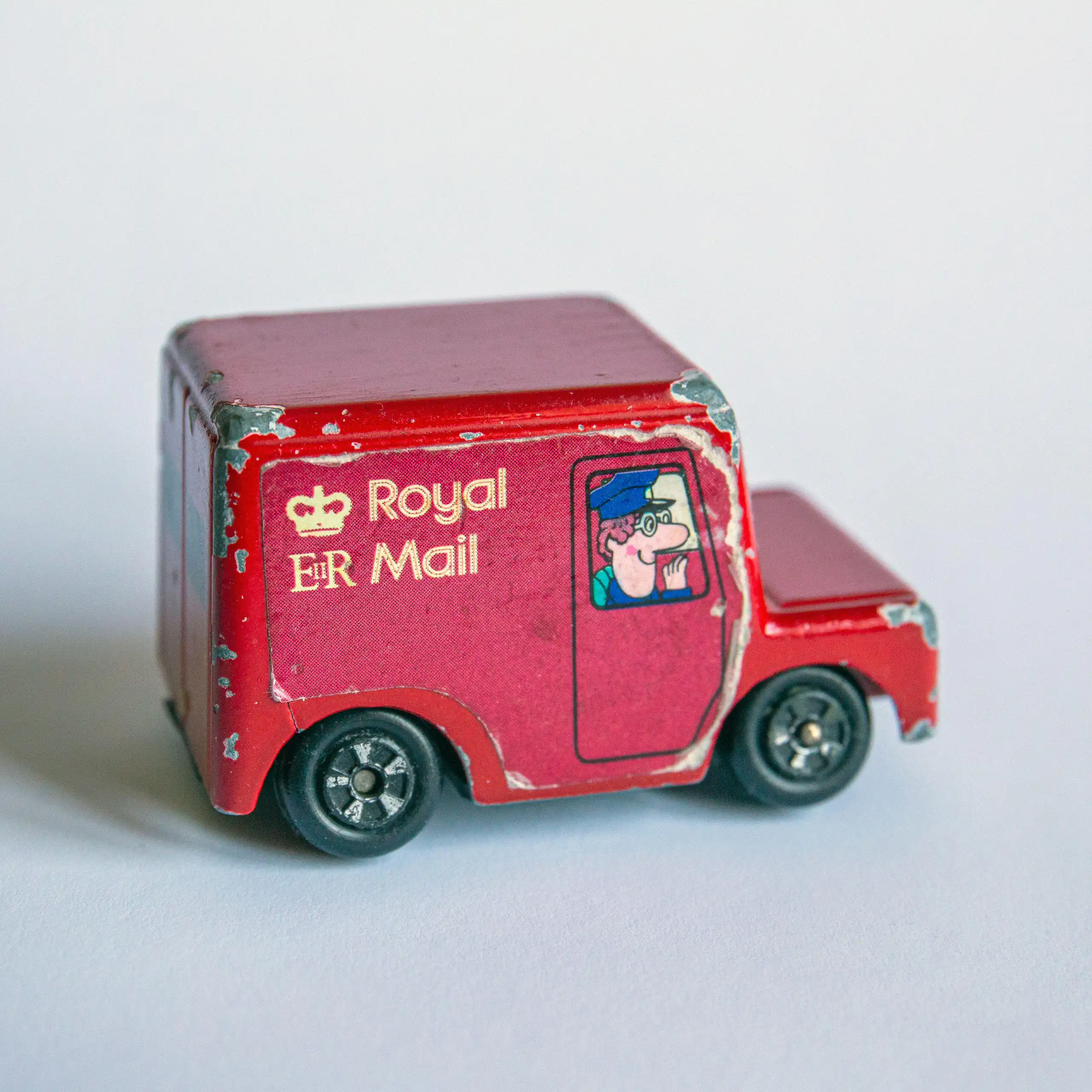 A toy post van with a drawing of Postman Pat in the window.