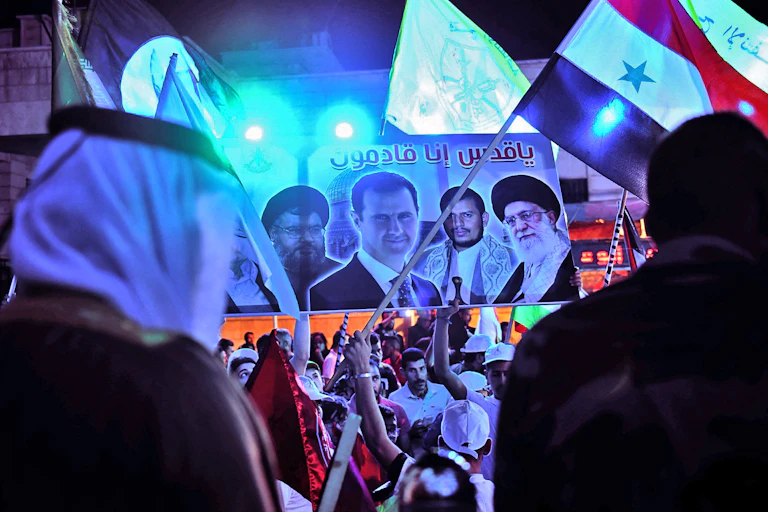 Men wave flags and a banner showing the face of four men.