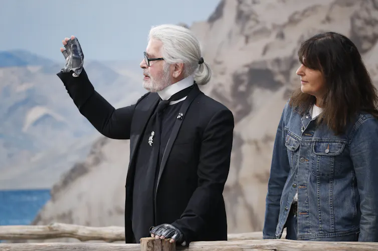 le directeur artistique de la maison Chanel, Karl Lagerfeld dit au revoir d'un signe de main. À ses côté, Viriginie Viard qui lui succèdera quelques mois plus tard