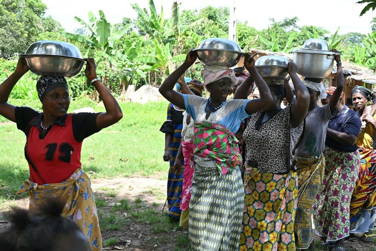 Women carrying metal bowls on their heads