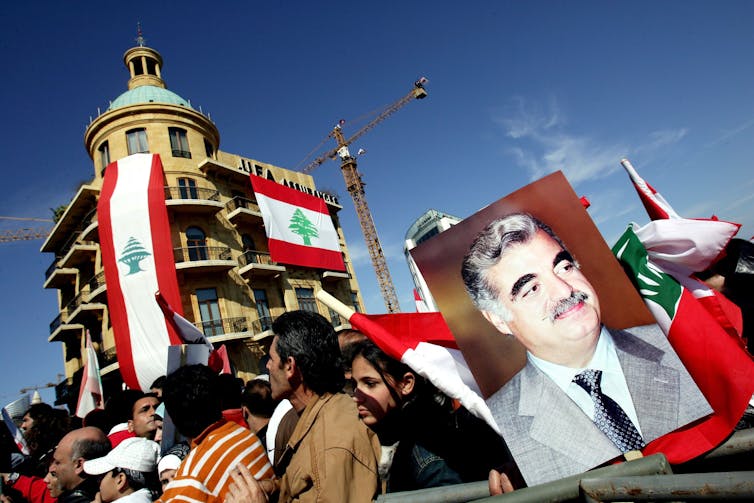 Protesters carrying red, white and green flags march. One holds a picture of a man.