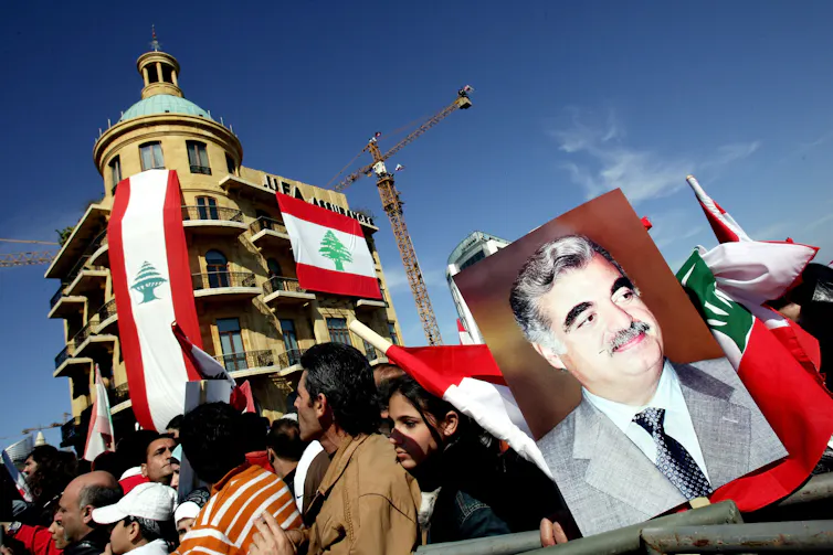 Protesters carrying red, white and green flags march. One holds a picture of a man.